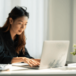 Female business owner reviewing documents in an office laptop.
