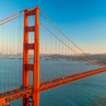 Panoramic view of the Golden Gate Bridge under a clear blue sky, featuring the company logo overlay to represent business loans and capital in California.