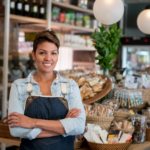 A smiling small business owner standing confidently inside her shop, illustrating the peace of mind provided by a small business safety net.