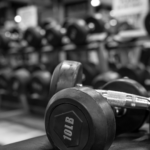 A close-up black and white photograph of a 10 lb dumbbell on a rack in a fitness studio, illustrating equipment funded by a gym business loan.