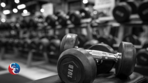 A close-up black and white photograph of a 10 lb dumbbell on a rack in a fitness studio, illustrating equipment funded by a gym business loan.